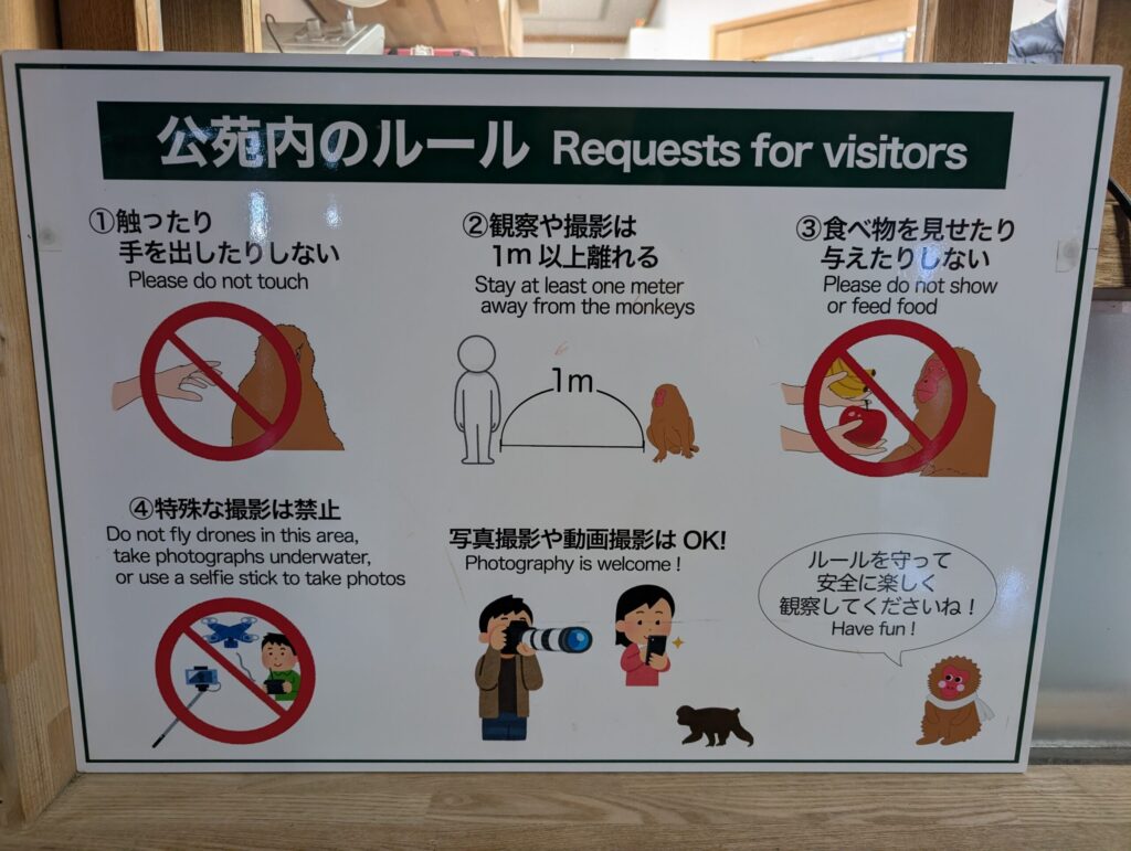 Visitor rules sign at Jigokudani Monkey Park explaining safety guidelines, including not touching or feeding monkeys, keeping at least one meter distance, and photography rules.