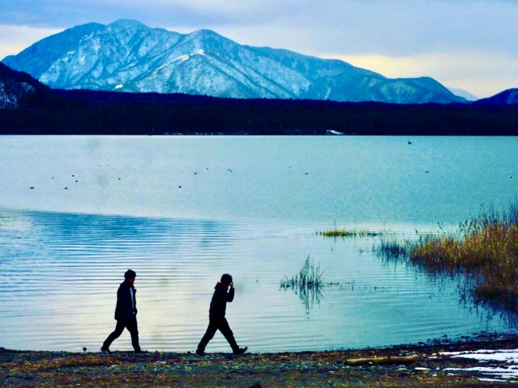 Visitors walking along the shoreline of Lake Saiko in the Fuji Five Lakes area, Japan