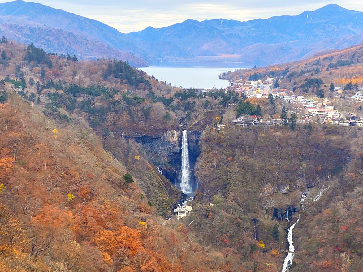 Panoramic view of Kegon Falls in Nikko National Park, with Lake Chuzenji and mountain ridges visible in the background during late autumn.